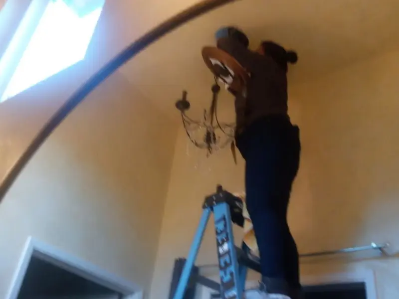Electrician installing a chandelier in a Primera residence